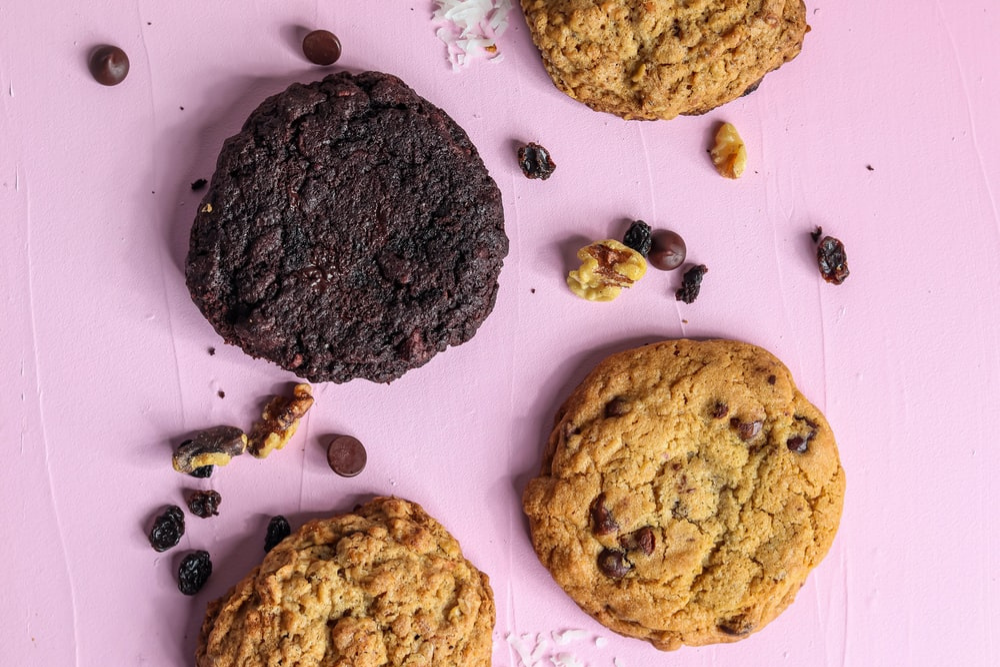 Flat lay of different coloured cookies on a pastel pink background